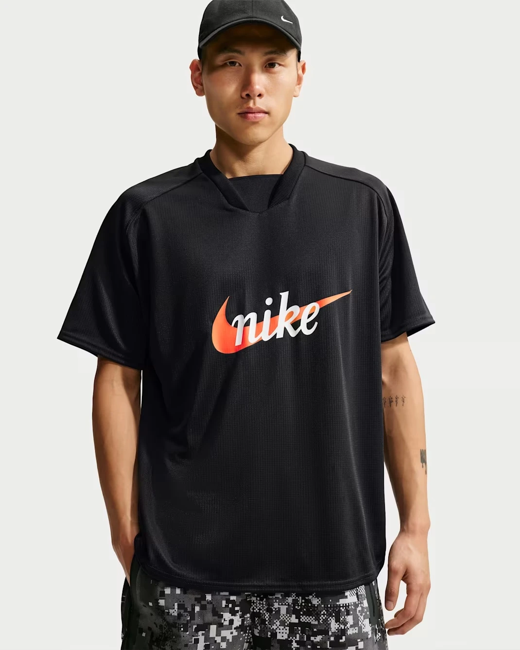 Nike Sportswear Club Jersey T-Shirt in Black with orange Nike graphic.