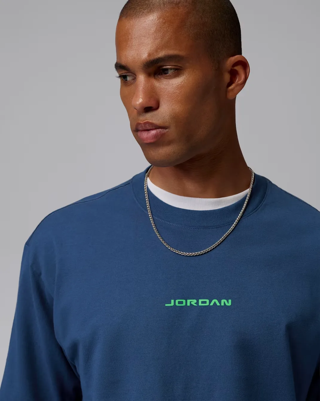 Close-up of the Jordan AJ13 Graphic T-Shirt in French Blue featuring a green Jordan logo on the chest.