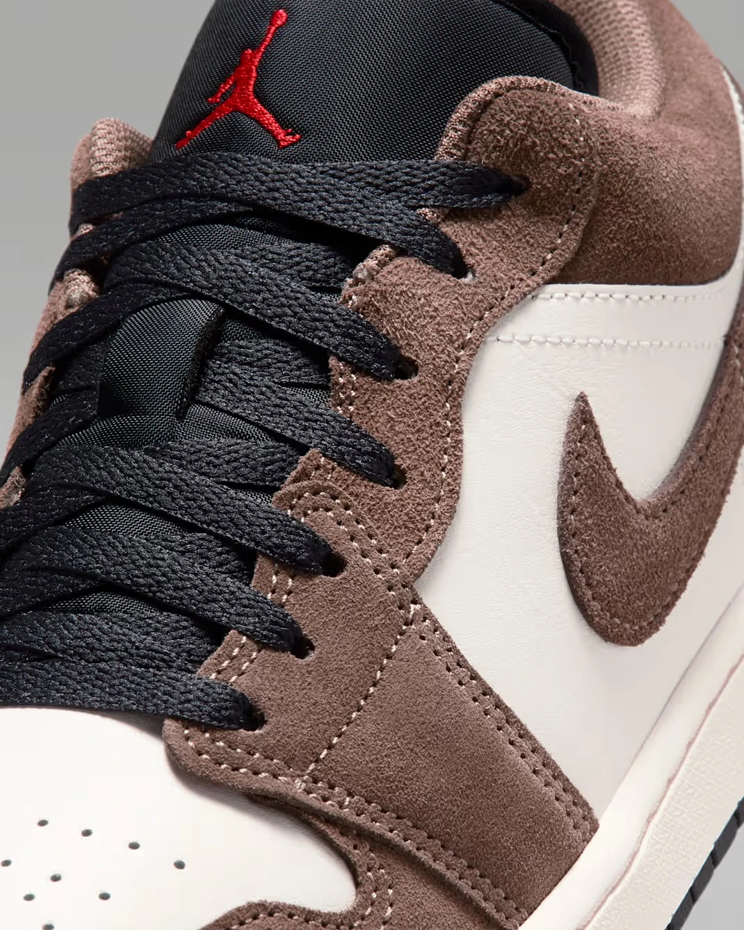 Close-up of the suede Swoosh and black laces on the Air Jordan 1 Low "Palomino/Phantom."