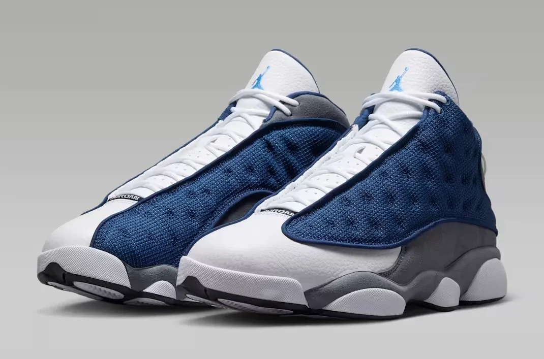 Angled pair view of the Air Jordan 13 Flint (2026) in Navy, University Blue, Flint Grey, and White.