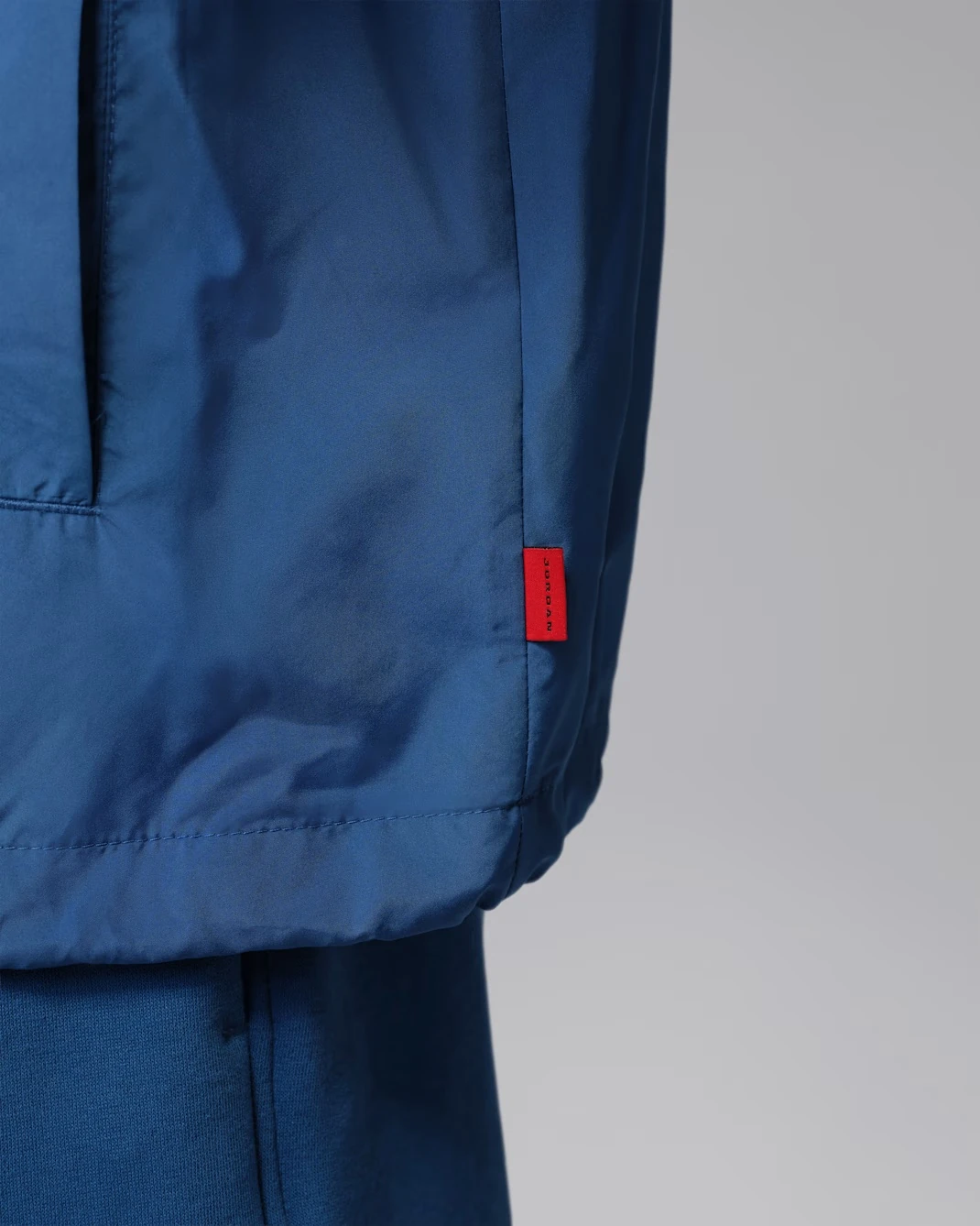 Close-up of the woven Jordan label stitched to the hem of the Jordan Brooklyn Coaches Jacket.