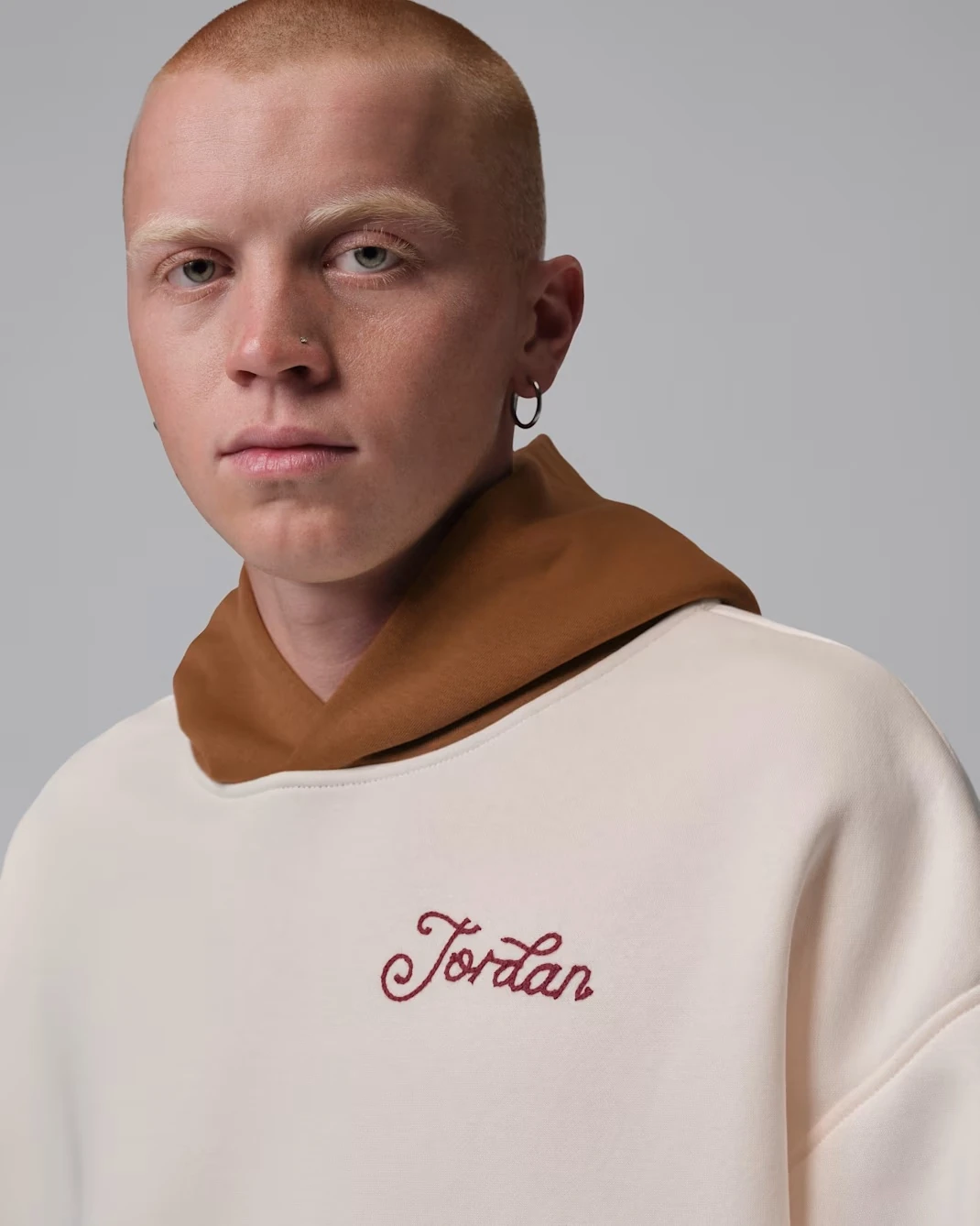 Model wearing the Jordan Brooklyn Fleece Men's Oversized Pullover Hoodie in Soft Pearl and Light British Tan.