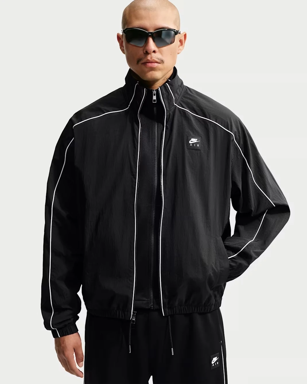 Front view of the Nike Air Men's Woven Track Jacket in black with white piping.