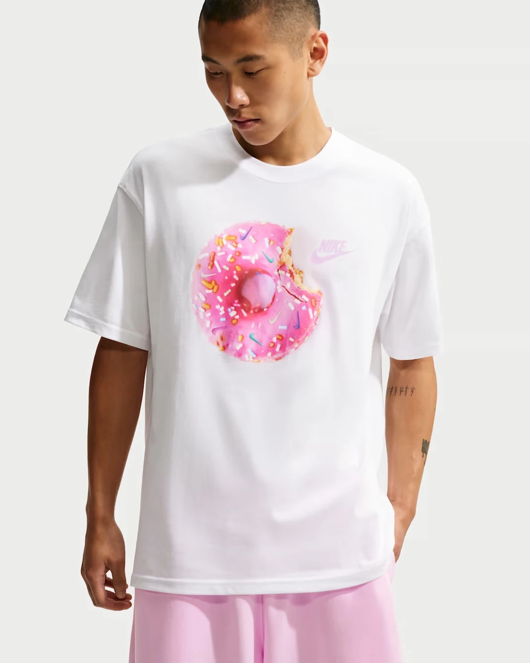 Front view of the Nike Sportswear "Donut" Men's T-Shirt in White featuring a pink donut graphic that matches the Nike Dunk Low "Pink Donut" sneakers.