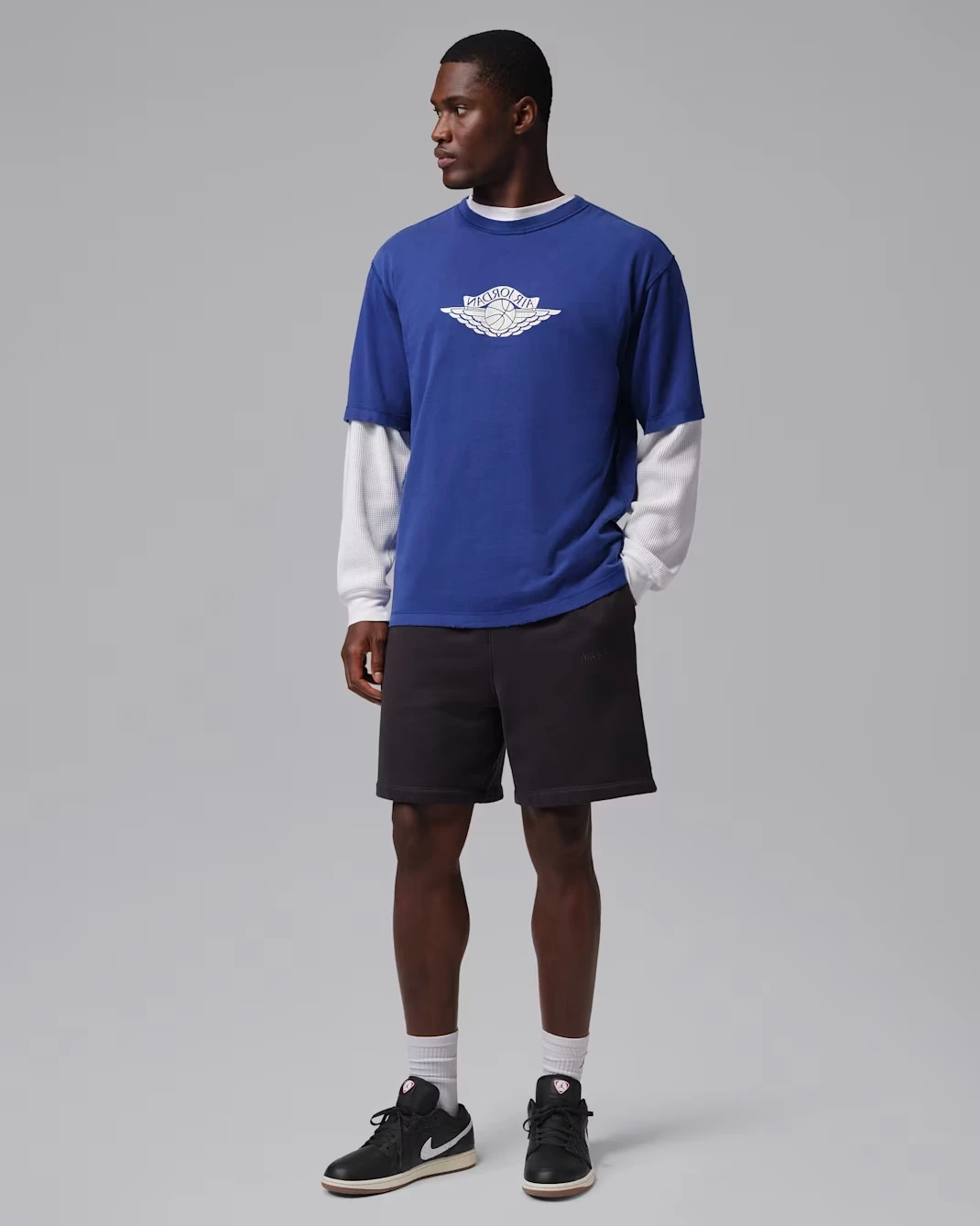 Model wearing the Air Jordan 1 Low SE Quilted "Off Noir" with a Game Royal Jordan shirt and black shorts.