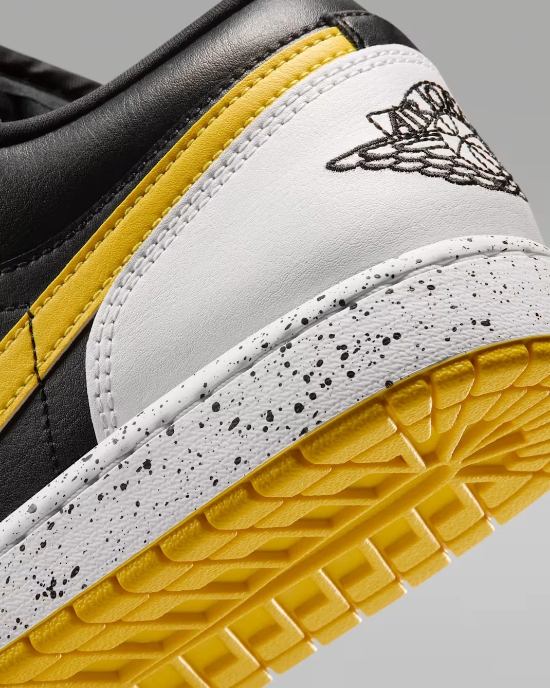 Close-up of the Air Jordan Wings logo, white heel, yellow accent and speckled midsole on the Air Jordan 1 Low Tour Yellow.