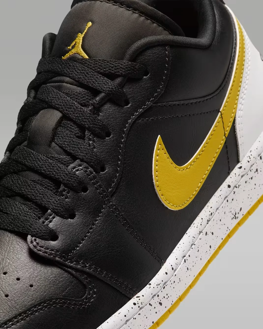 Close-up of the Tour Yellow Nike Swoosh and black upper on the Air Jordan 1 Low Tour Yellow.