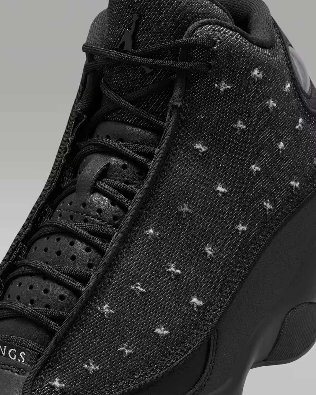 Close-up of the embroidered textile upper and black leather tongue on the Air Jordan 13 Retro Wings.