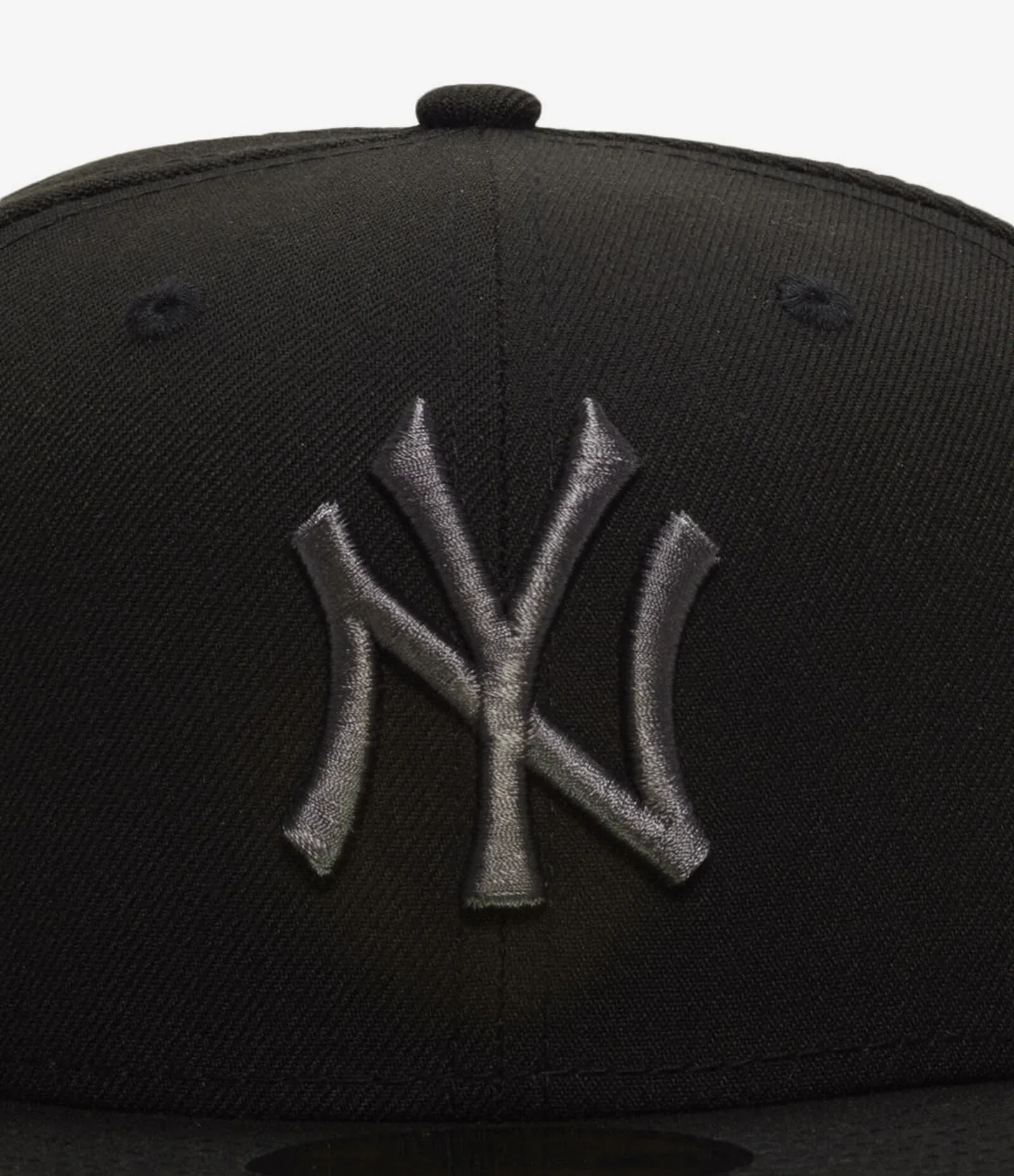 Close-up of the graphite New York Yankees logo on the black New Era 59FIFTY fitted hat.