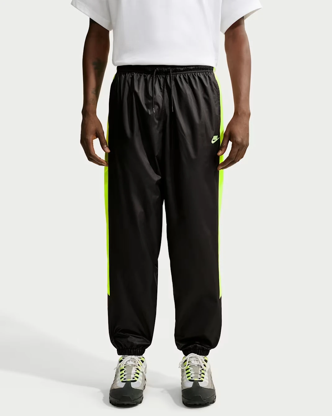 Front view of the Nike Windrunner Lined Pants in Black with Neon Yellow side panels.