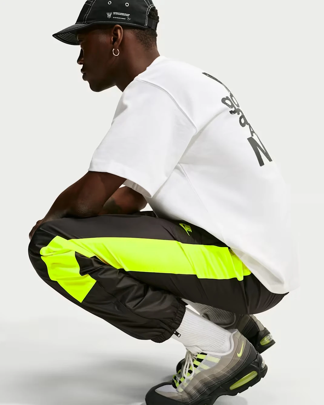 Model wearing Nike Windrunner Lined Pants in Black with Neon Yellow side panels.