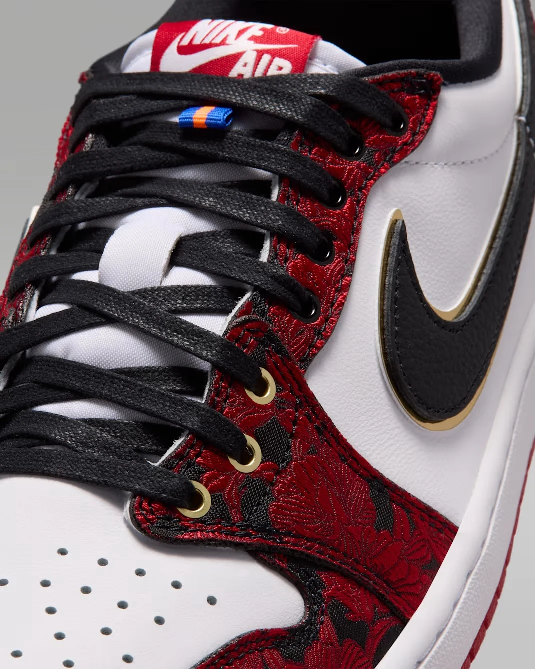 Close-up of the Air Jordan 1 Low OG Welcome to the Garden with black laces, red floral overlays and gold accents.