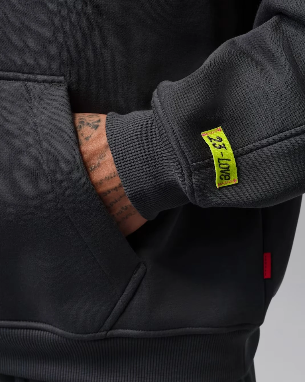 Lime Blast 23-Love sleeve tag on the Anthracite Jordan Brooklyn Fleece hoodie.