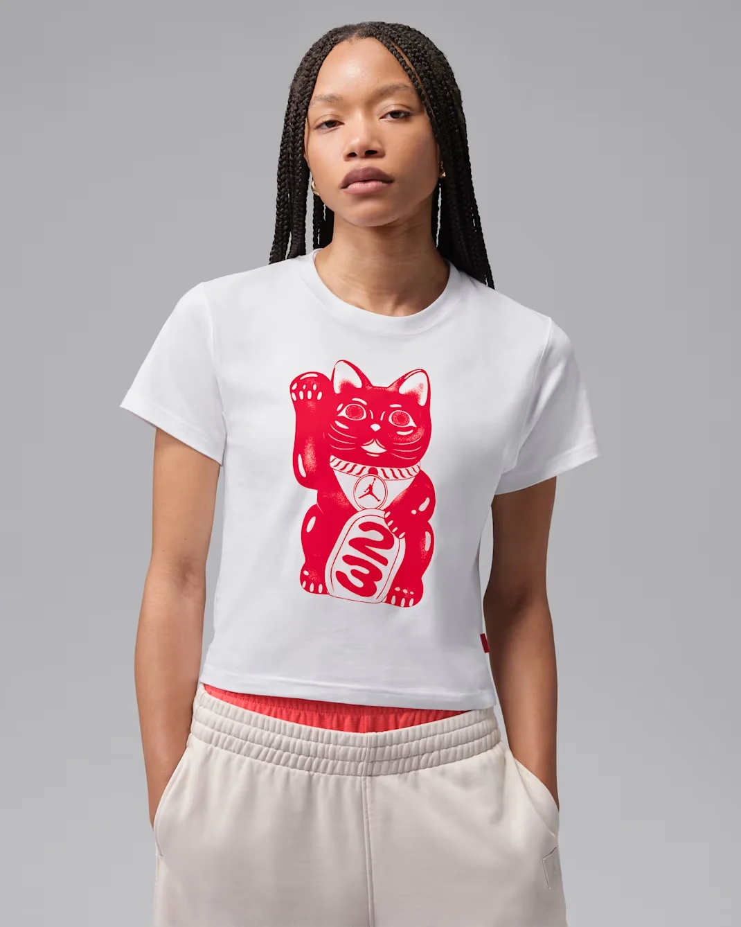 Woman wearing a white Jordan Lucky Cat graphic T-shirt with a red graphic.