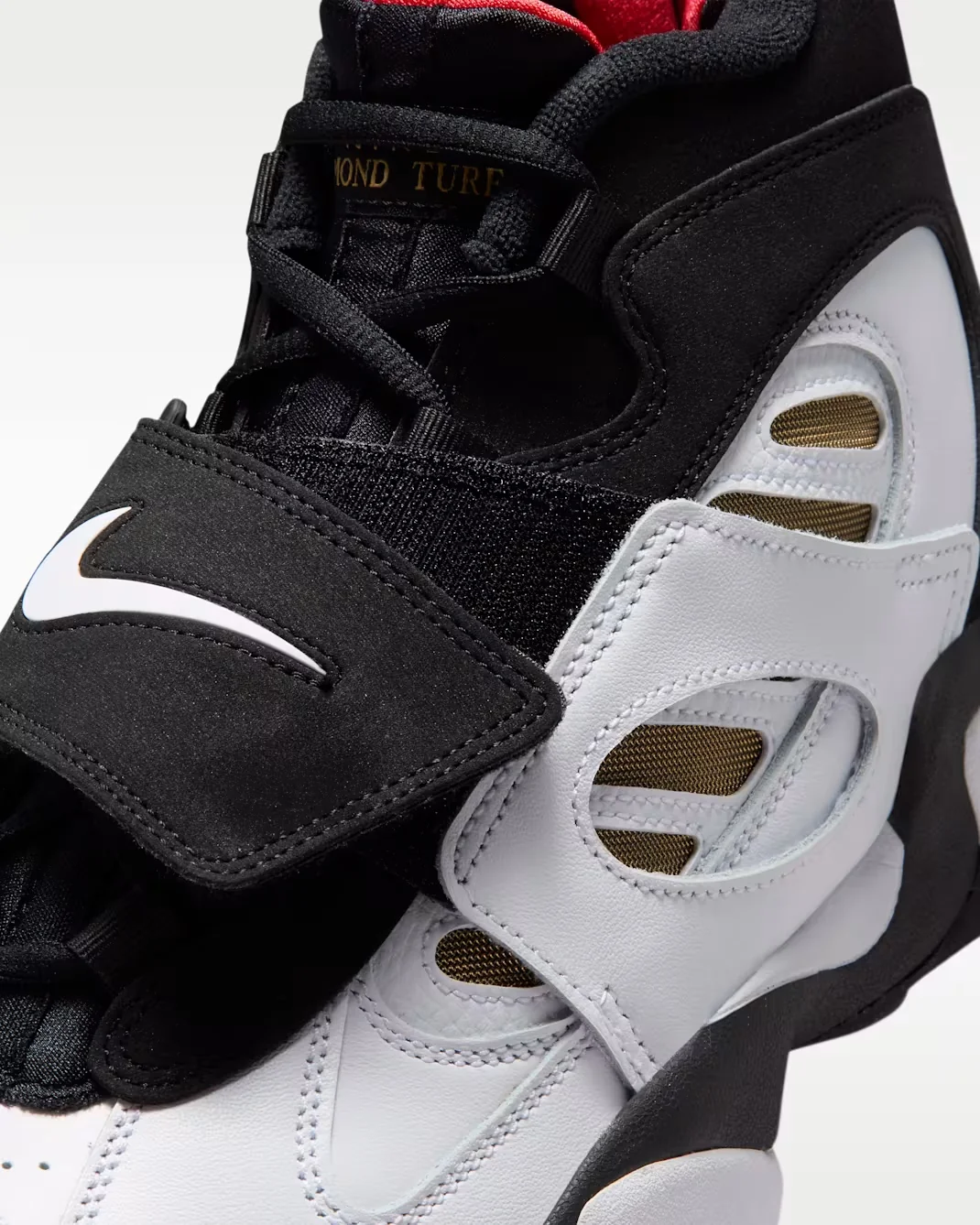 Close-up of the Nike Air Diamond Turf 2 black midfoot strap, white overlays and Metallic Gold mesh.
