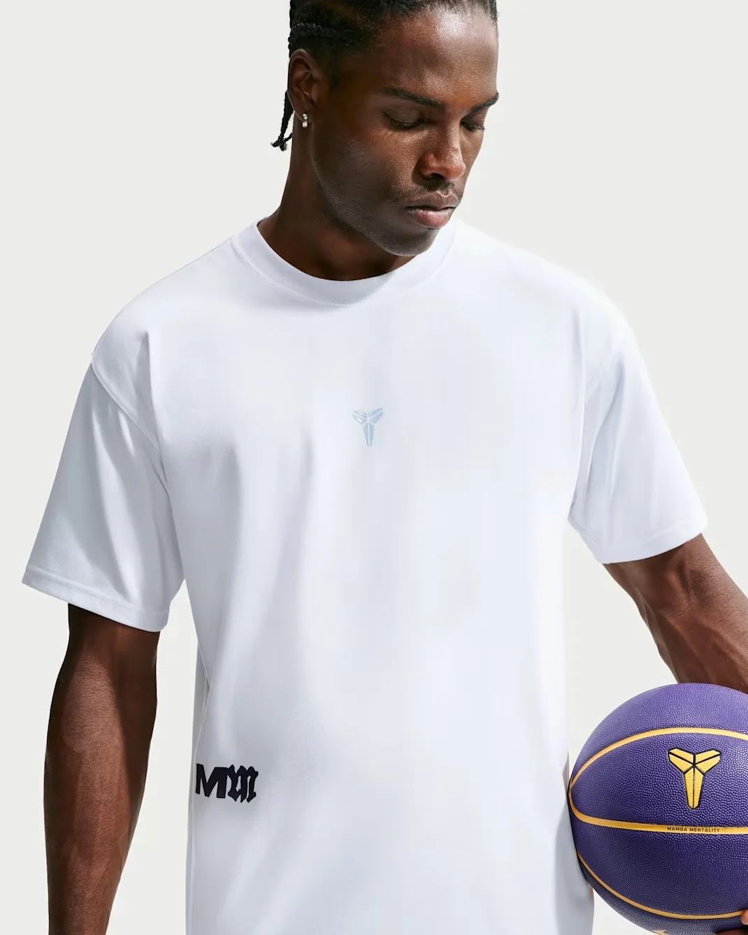 White Nike Kobe Mamba Mentality T-shirt with light blue and black details next to a purple Kobe basketball.