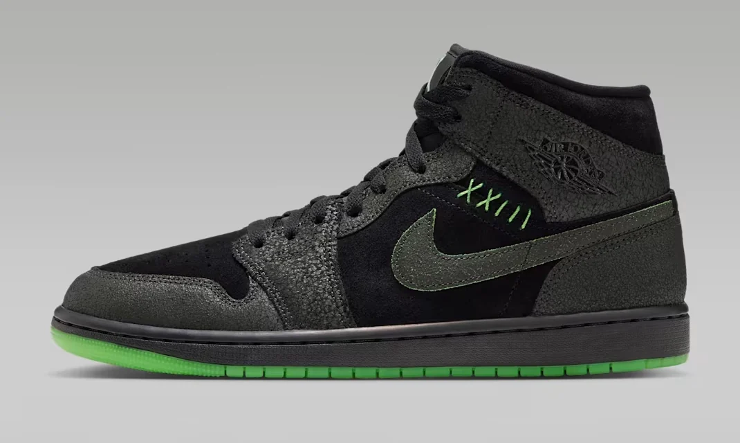 Air Jordan 1 Mid SE Halloween sneaker featuring black and dark grey textured overlays, green stitching, a grey Nike Swoosh and bright green outsole, shown from the side.