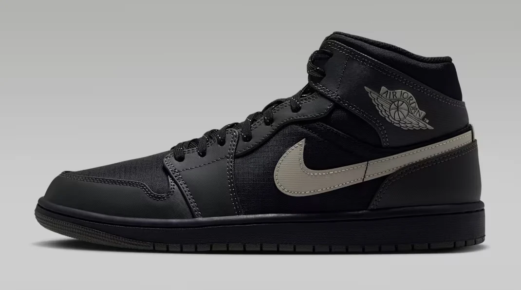 Air Jordan 1 Mid Utility Black/Newsprint sneaker featuring a black upper, grey Nike Swoosh, reflective detailing and Air Jordan Wings branding.