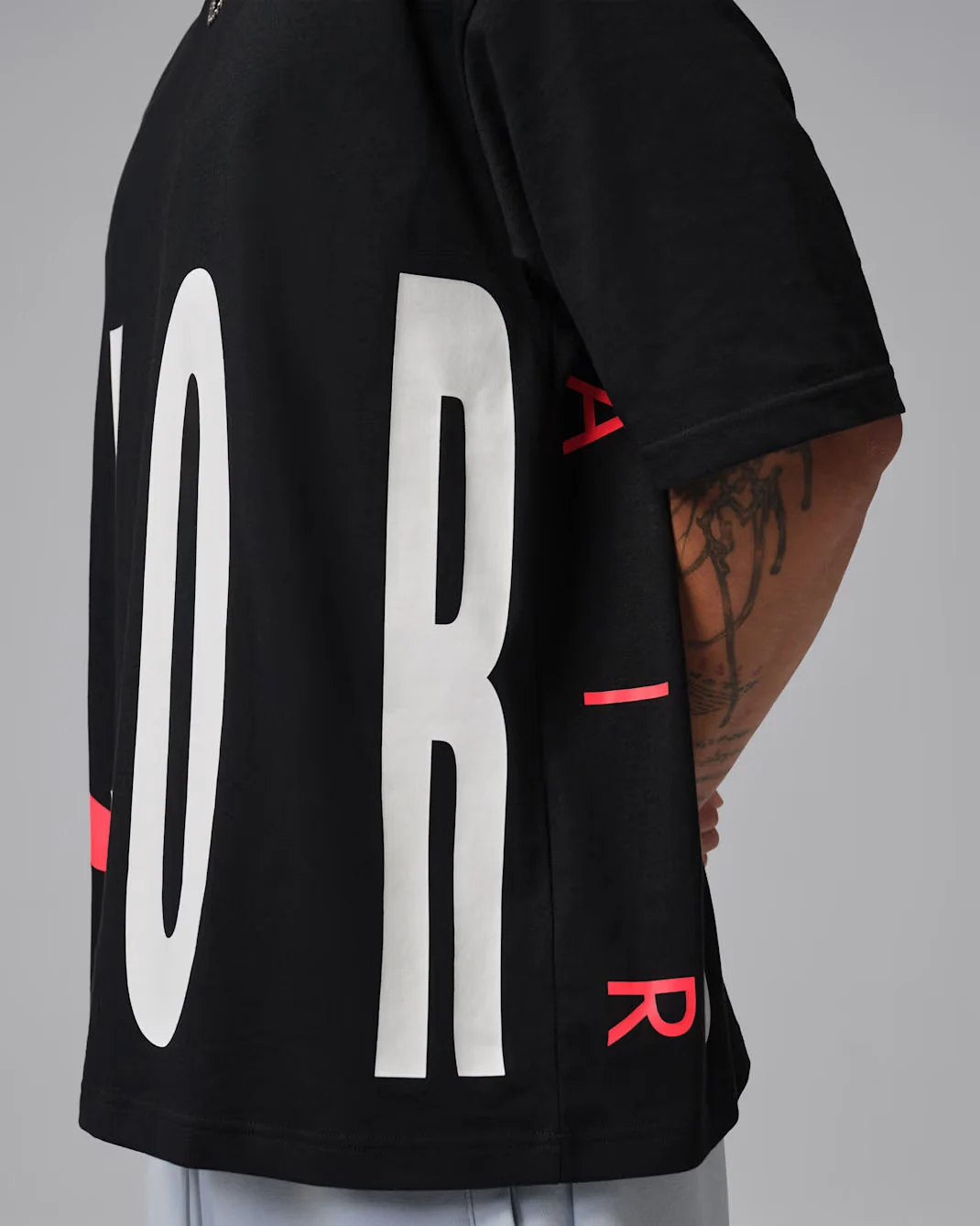 Close-up of black Jordan Torso Stretch Oversized T-Shirt showing large white lettering and Infrared graphic accents, coordinating with the Air Jordan 6 White Infrared.