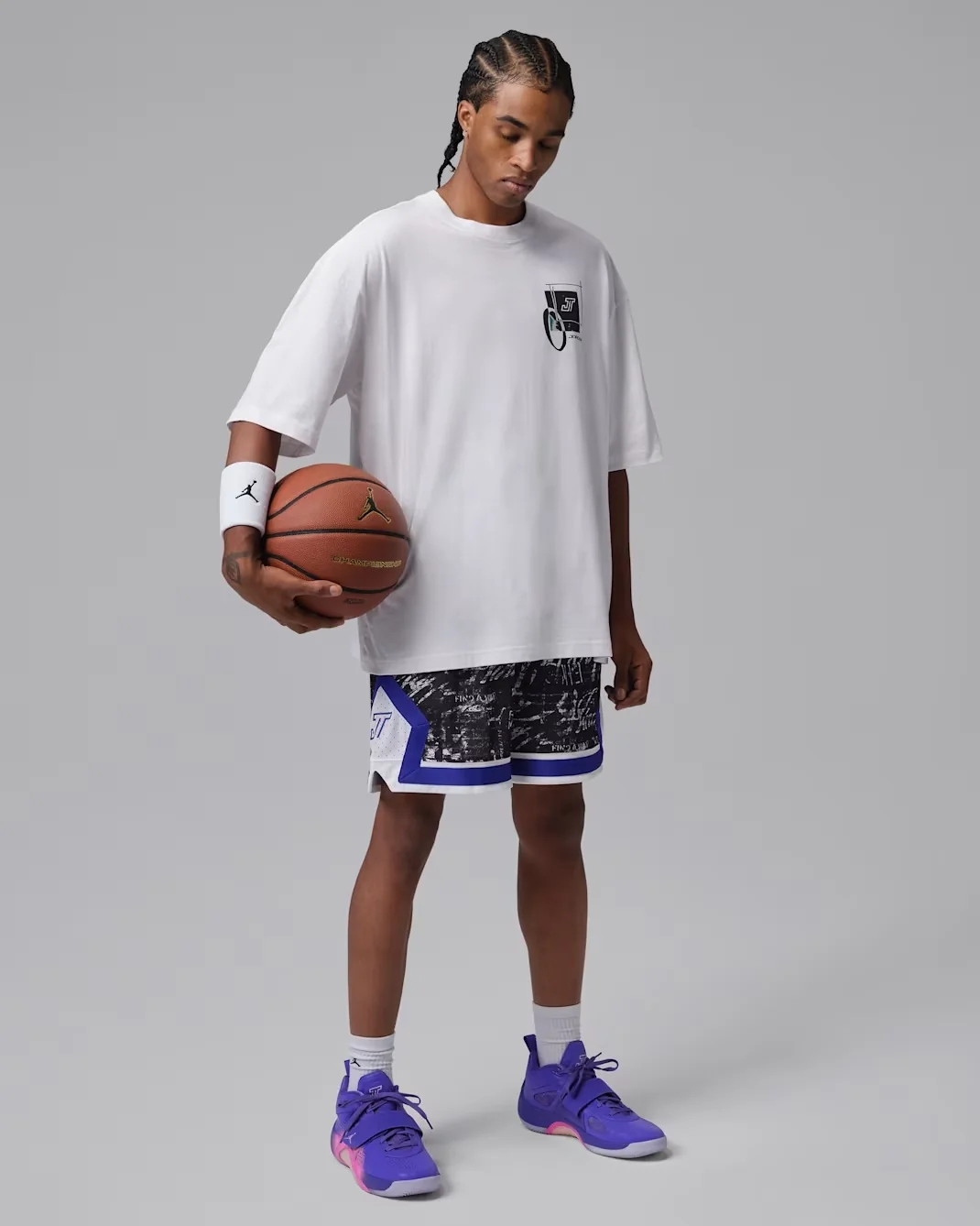 Jordan Tatum 5 Sunrise outfit featuring purple and pink sneakers, a white Tatum Sport T-shirt and black, white and blue basketball shorts.