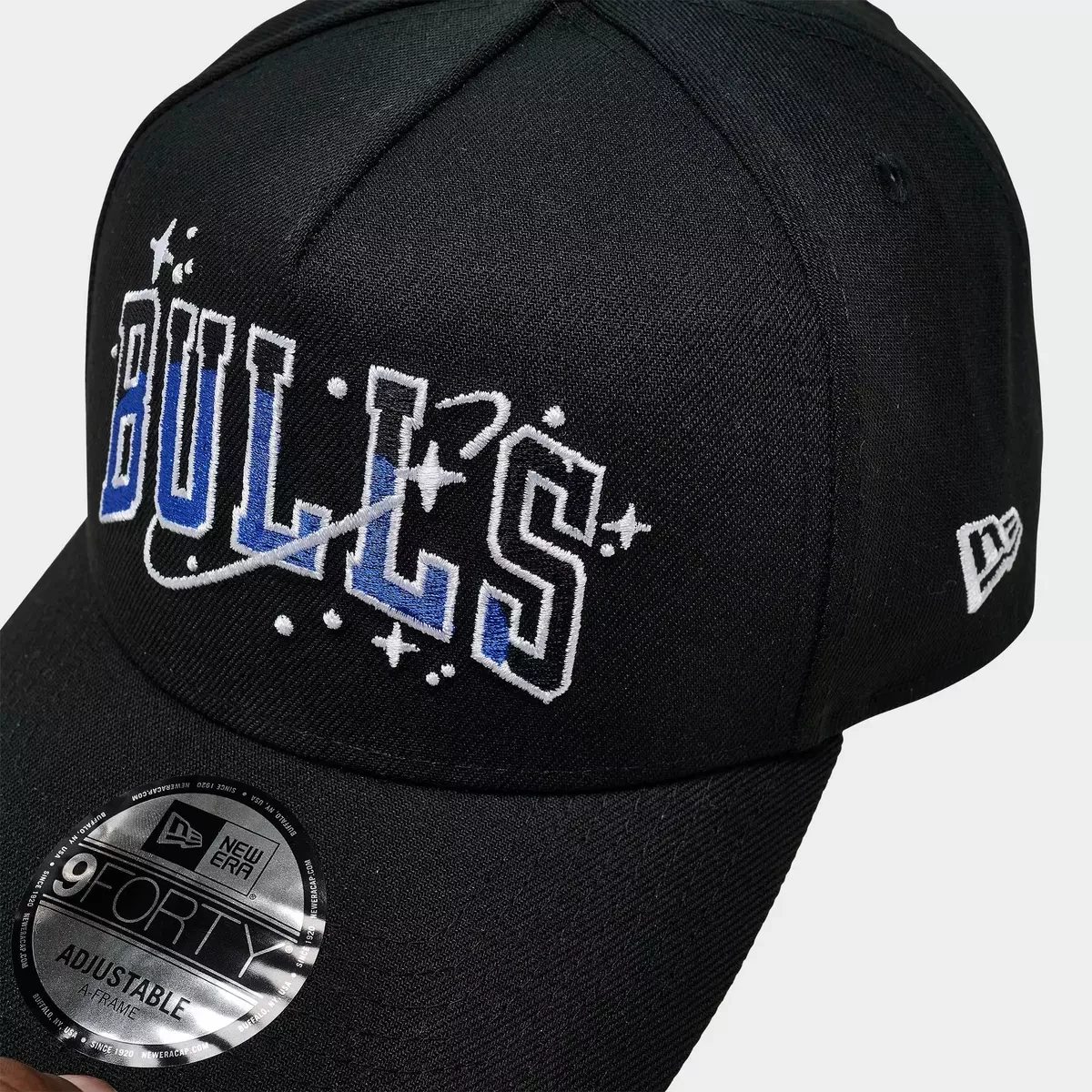 Close-up of blue and white Chicago Bulls lettering with embroidered stars and orbital graphics on black New Era Space Galaxy hat.