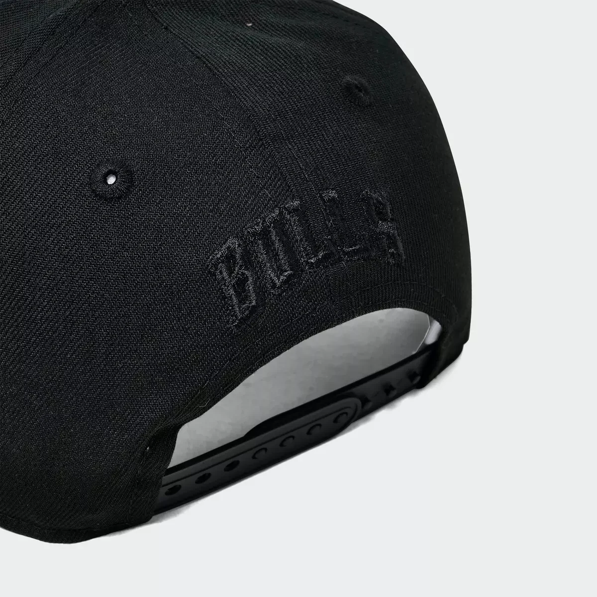 Close-up of black Chicago Bulls Space Galaxy New Era hat showing black-on-black Bulls embroidery and adjustable snapback strap.
