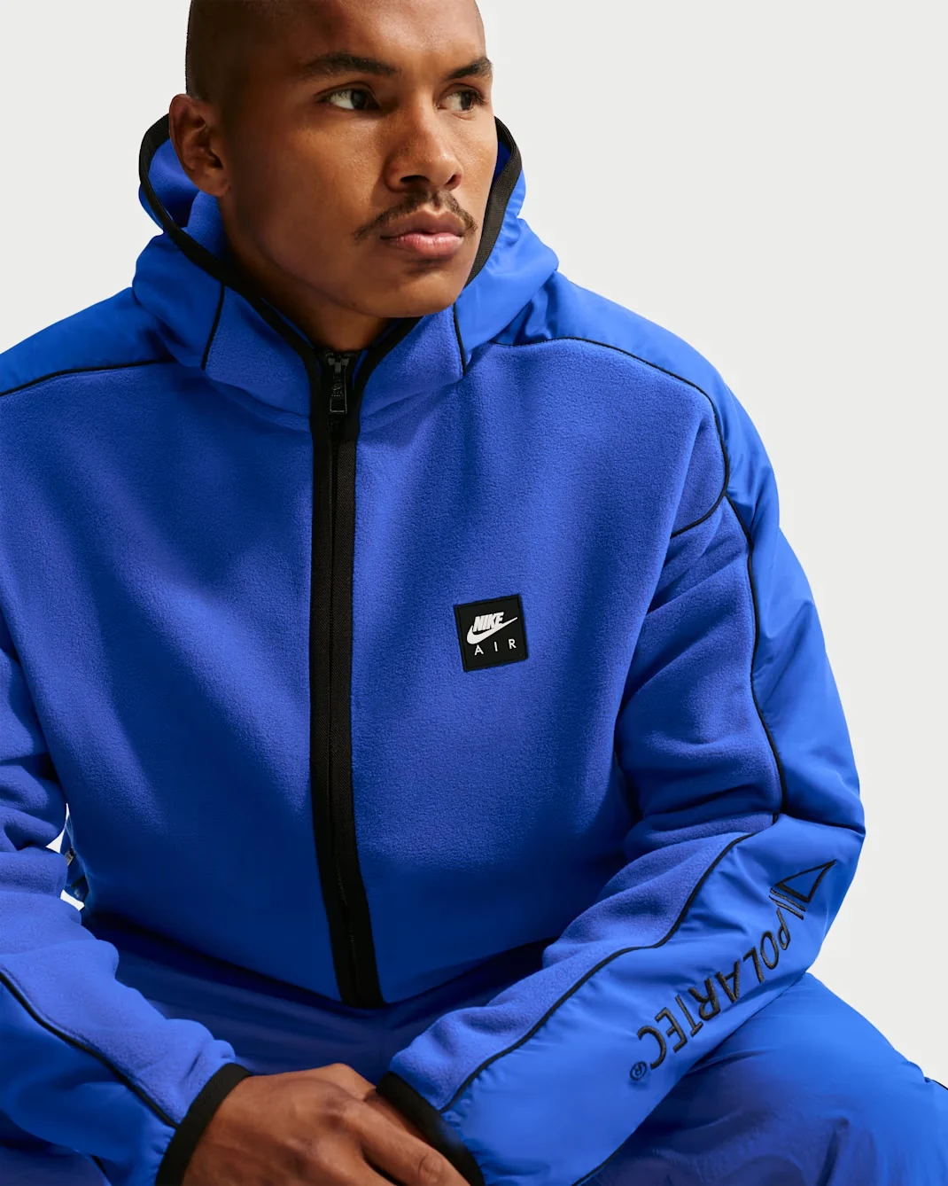 Model wearing royal blue Nike Air Polartec Therma-FIT full-zip hooded track jacket with black zipper and trim