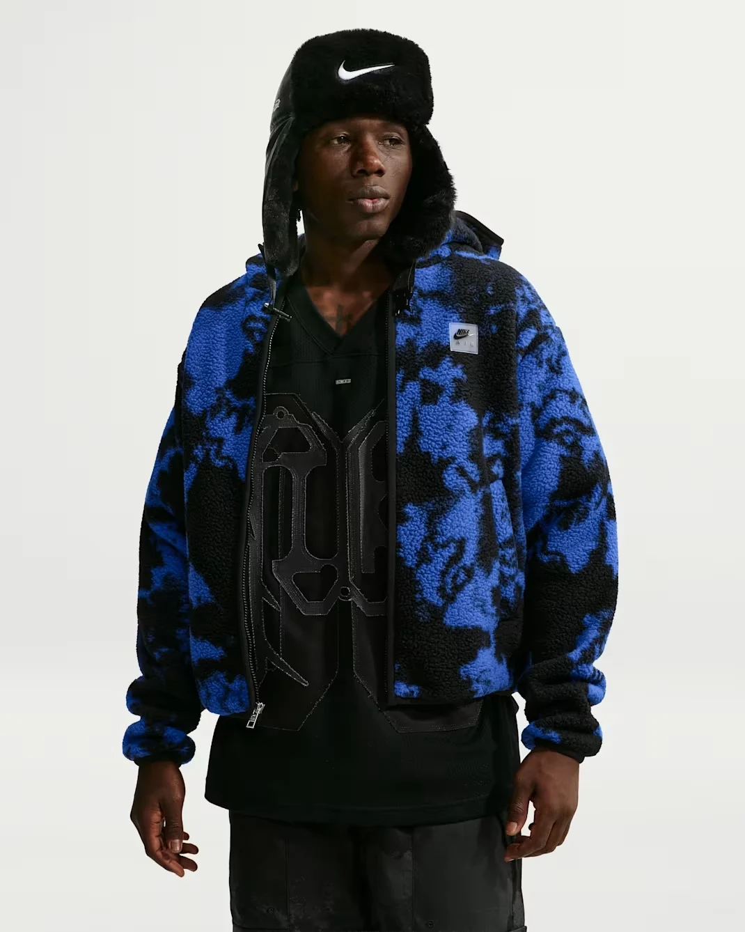 Model wearing royal blue and black Nike Air sherpa full-zip jacket with patterned fleece and chest logo