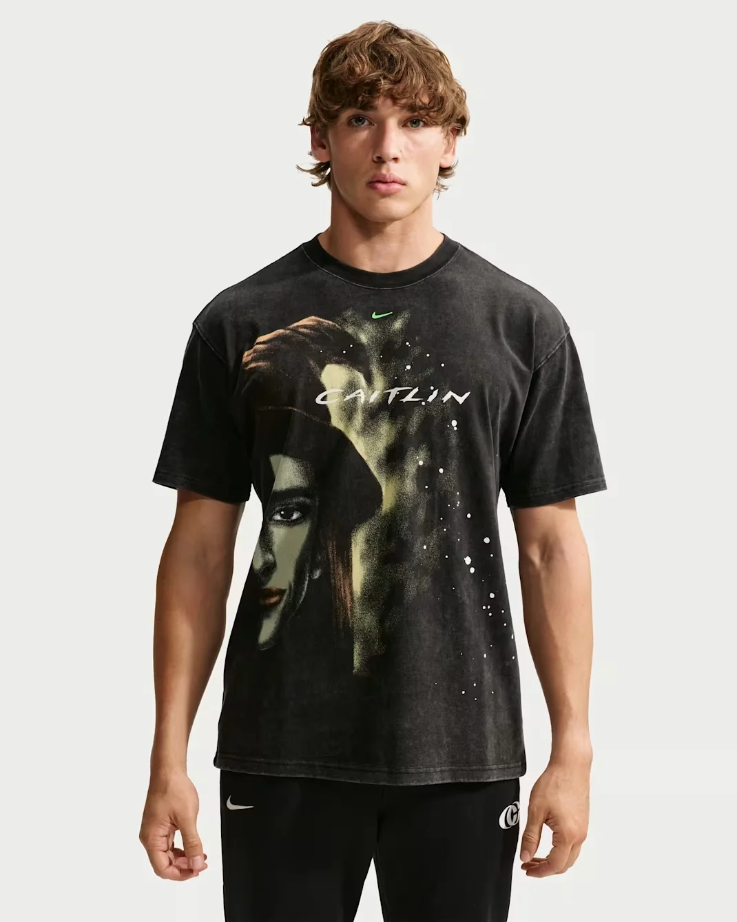 Model wearing the black Nike Caitlin Clark Halloween basketball T-shirt with a green-tinted portrait graphic and white Caitlin lettering.