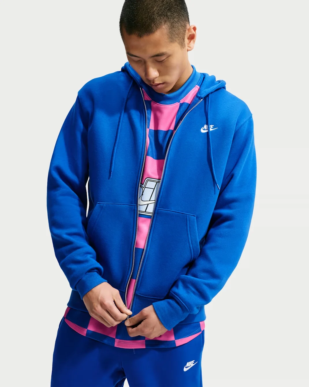 Model wearing royal blue Nike Club full-zip fleece hoodie with white Nike logo