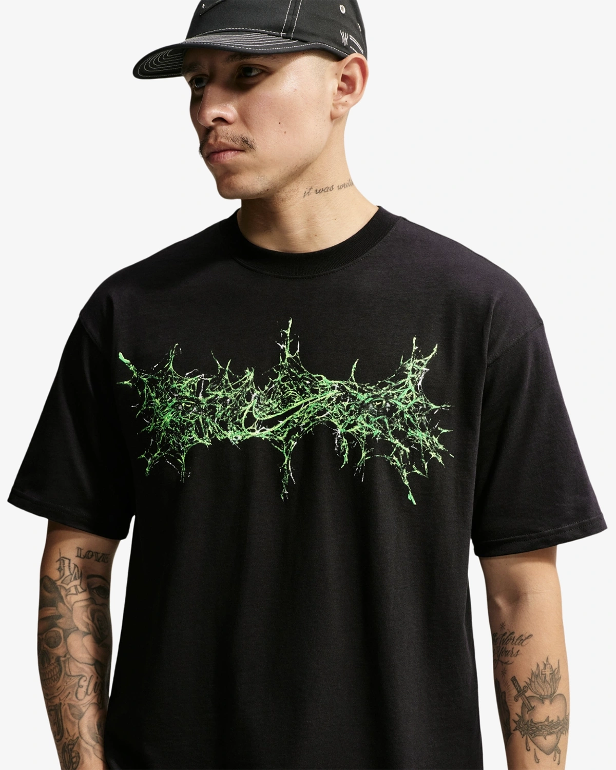 Model wearing the black Nike Halloween Max90 T-Shirt featuring a green spiderweb-inspired Nike graphic across the chest.