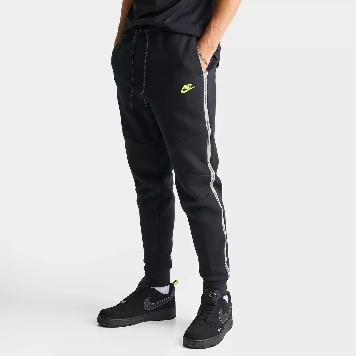 Nike Tech Fleece Reflective Jogger Pants in Black, Flat Pewter and Volt shown from the front with matching Nike Air Force 1 sneakers.
